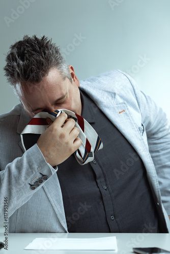 Man blows nose into tie, desperate expression photo