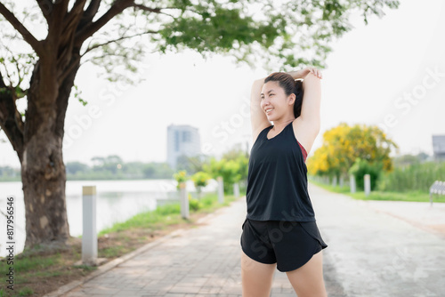 Asian woman stretching to warm up before going for a run in the park. Hair care concept before exercise to reduce injuries. Health care affected by sports. © Worranan