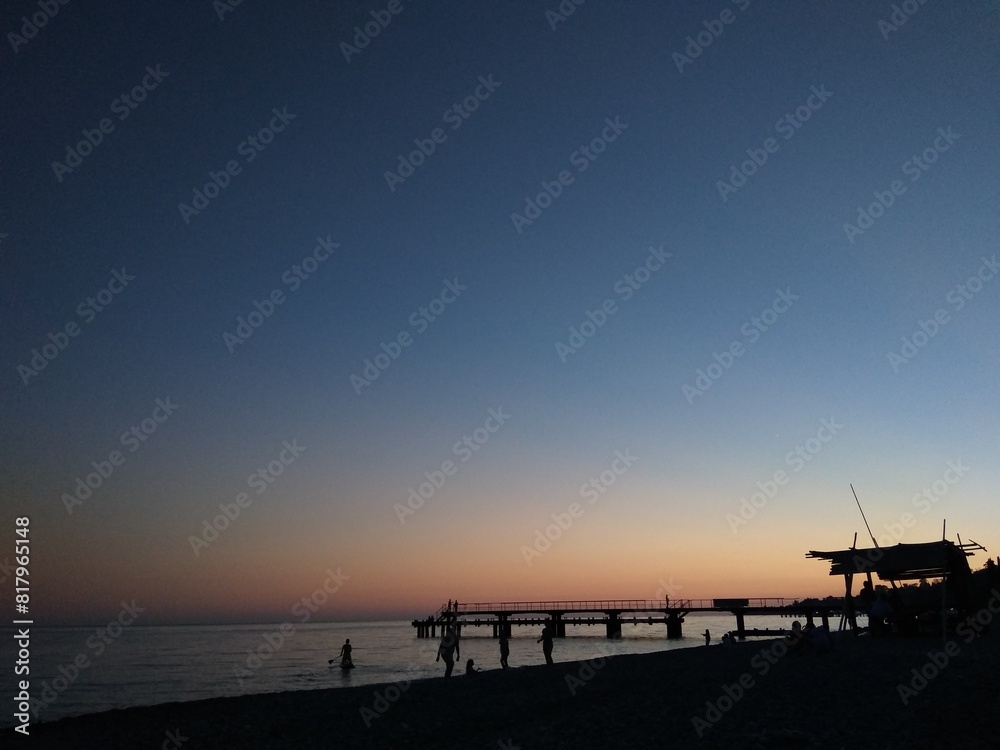 Sunset on the sea. Blue-orange. People and pier, contrasts Sunset on the sea. Blue-orange. People and pier, contrasts