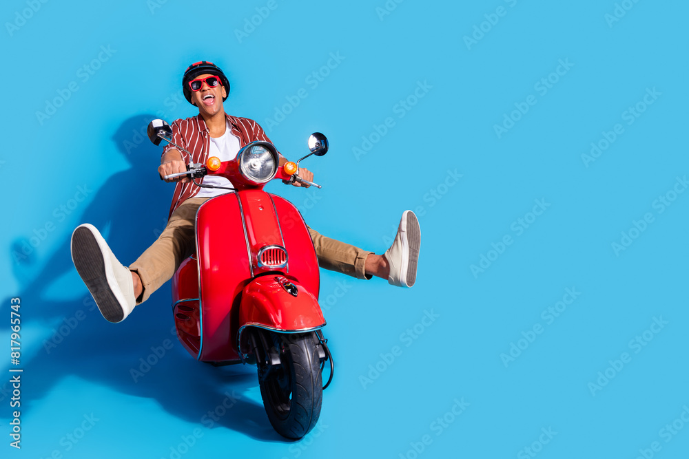 Full size photo of optimistic ecstatic man dressed striped shirt trousers ride motorcycle fast speed isolated on blue color background Full size photo of optimistic ecstatic man dressed striped shirt trousers ride motorcycle fast speed isolated on blue color background