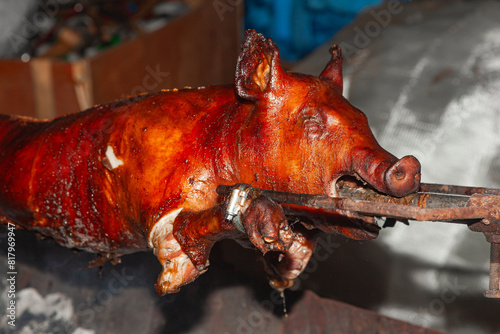 Photos A young pig is roasted on a spit over coals.