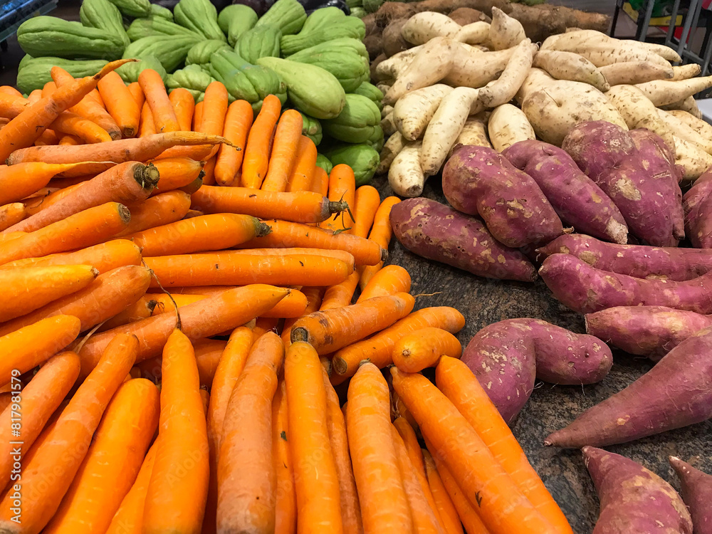 Carrots, sweet potatoes, and chayotes in bulk in the produce section of the supermarket.