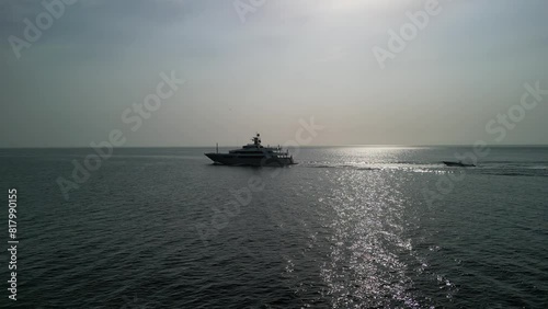 A luxury yacht on calm seas towing their tender. 