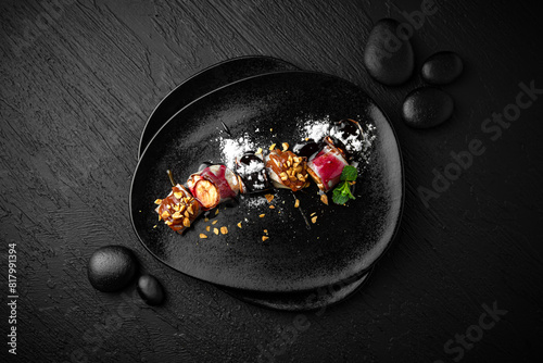 Fototapeta Naklejka Na Ścianę i Meble -  Japanese dessert sweet roll with banana, cream in rice paper. Composition on black background. The Art of Japanese Cuisine. Food photography for menu and sushi bar decoration