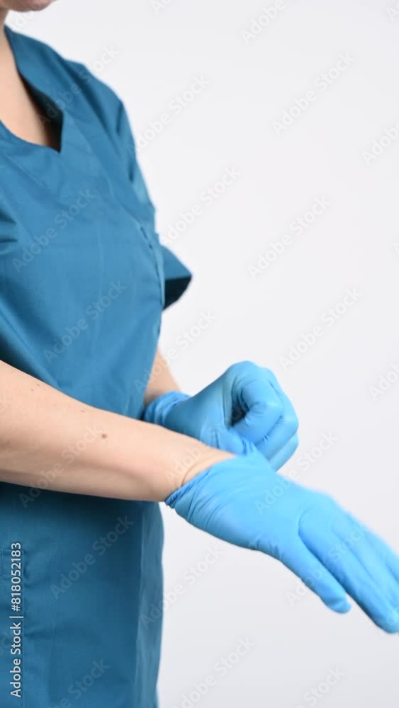 The doctor puts on latex gloves on a white background. Vertical video. The doctor puts on latex gloves on a white background. Vertical video.