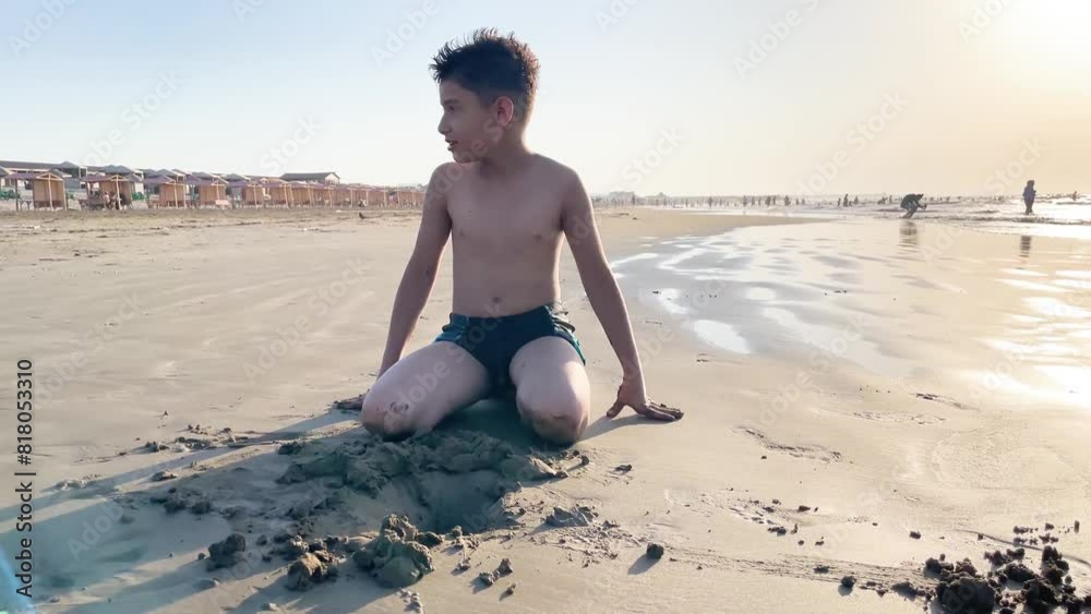 a boy digs a hole on the seashore