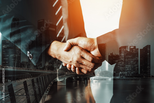Double exposure image of business people handshake on city office building in background showing partnership success of business deal. Concept of corporate teamwork, trust partner and work agreement. photo
