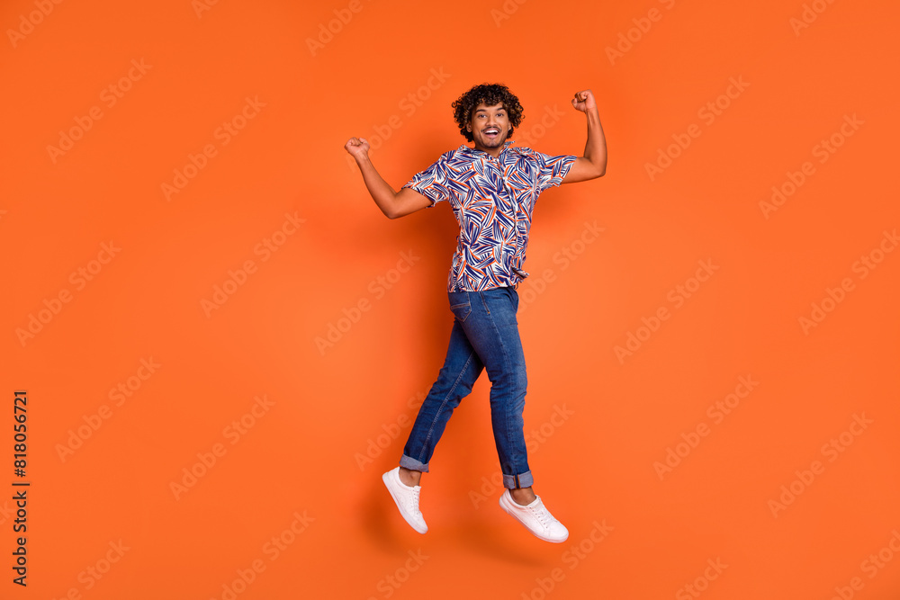 Full body photo of attractive young man jump winning dressed stylish colorful clothes isolated on orange color background Full body photo of attractive young man jump winning dressed stylish colorful clothes isolated on orange color background