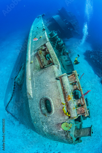 Scuba diver swimming alongside the bow of the Kittiwake shipwreck on the seabed, Seven Mile Beach, Grand Cayman, Cayman Islands, Caribbean Sea. 