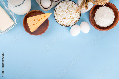 Various dairy organic foods background containing cheese, cottage cheese, eggs, milk, sour cream, cream, butter, wheat copy space