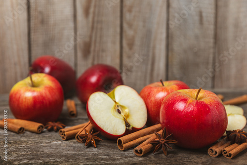 Fototapeta Naklejka Na Ścianę i Meble -  Apples with cinnamon on a textured wooden background. Fragrant red spiced apples with cinnamon sticks and star anise. Apple slices with spicy spices. Place for text. Copy space. Harvesting. Fruits. 