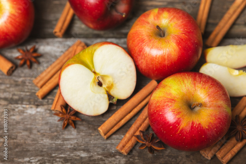 Apples with cinnamon on a textured wooden background. Fragrant red spiced apples with cinnamon sticks and star anise. Apple slices with spicy spices. Place for text. Copy space. Harvesting. Fruits. 