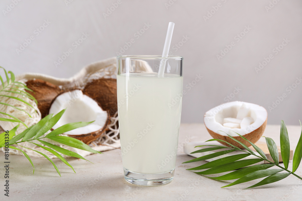 Glass of coconut water, palm leaves and nuts on light table Glass of coconut water, palm leaves and nuts on light table