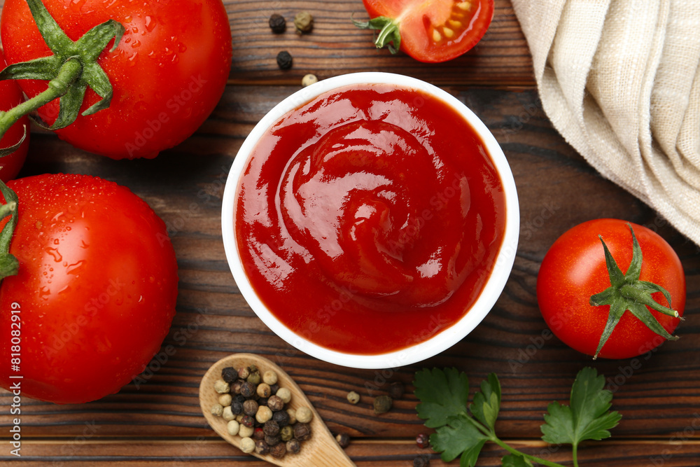 Delicious ketchup in bowl, tomatoes and peppercorns on wooden table, flat lay Delicious ketchup in bowl, tomatoes and peppercorns on wooden table, flat lay