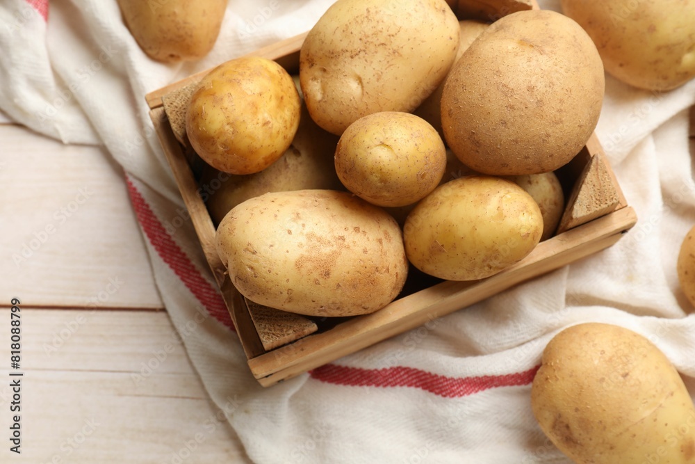 Raw fresh potatoes with crate on light wooden table, top view Raw fresh potatoes with crate on light wooden table, top view