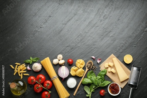 Different types of pasta, spices, garter and products on dark textured table, flat lay. Space for text