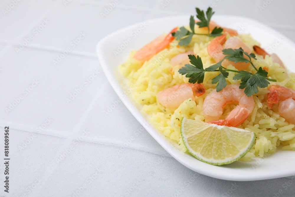 Delicious risotto with shrimps, lime and parsley on white tiled table, closeup. Space for text Delicious risotto with shrimps, lime and parsley on white tiled table, closeup. Space for text