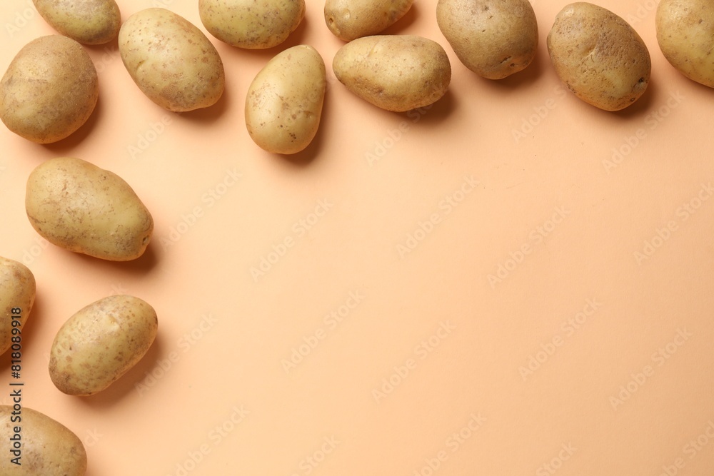 Fresh raw potatoes on pale orange background, flat lay. Space for text Fresh raw potatoes on pale orange background, flat lay. Space for text