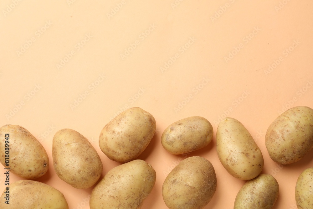 Fresh raw potatoes on pale orange background, flat lay. Space for text Fresh raw potatoes on pale orange background, flat lay. Space for text