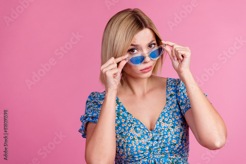 Photo of doubtful attractive lady dressed blue top dark glasses looking you empty space isolated pink color background © deagreez