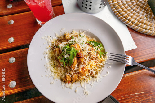 Risotto with chicken meat with curcuma, grated cheese and rucola leaf on white plate.