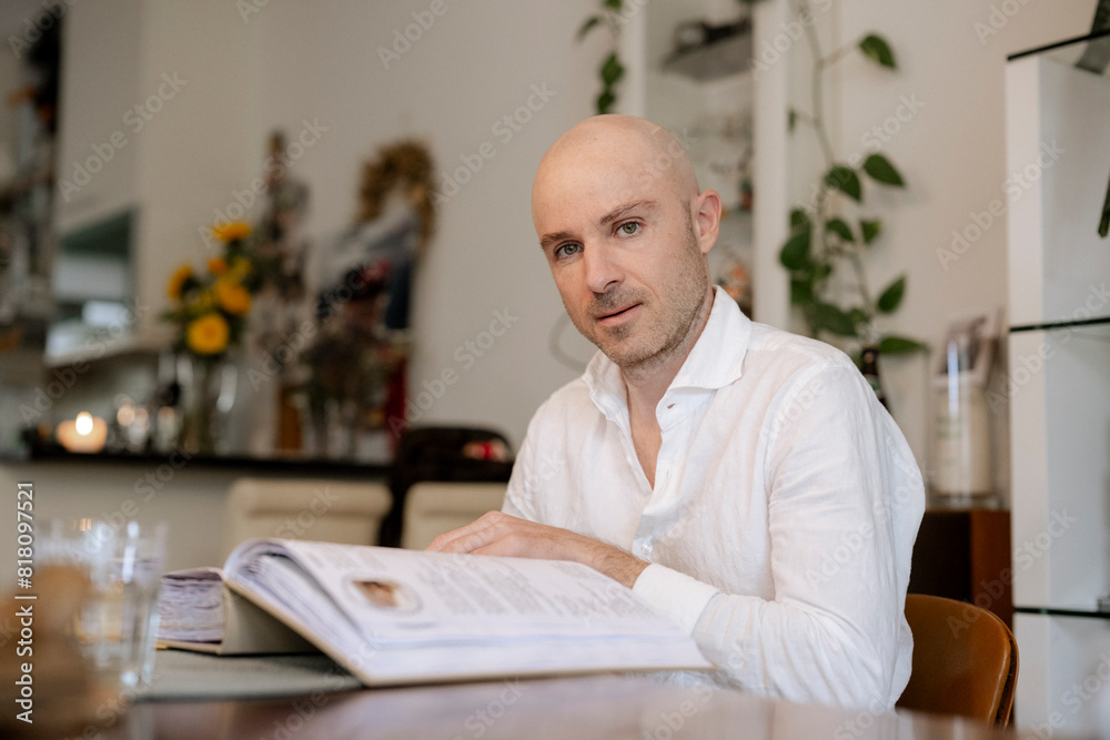 Mann sitzt an einem Tisch und blättert in einem Album Mann sitzt an einem Tisch und blättert in einem Album