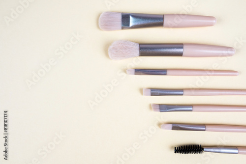 Makeup brushes on a beige background with copy space.