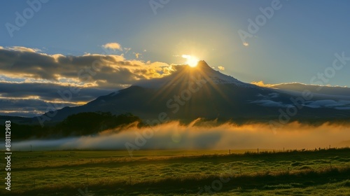 A serene moment as the sun sets behind a mountain casting its shadow onto the lowhanging clouds. photo