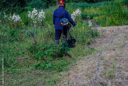 A man cuts and mows the grass. Grass cutting work. Worker mows lawn with grass photo