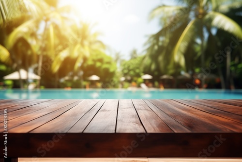 Mesa de madera vacía frente a piscina con fondo tropical desenfocado.