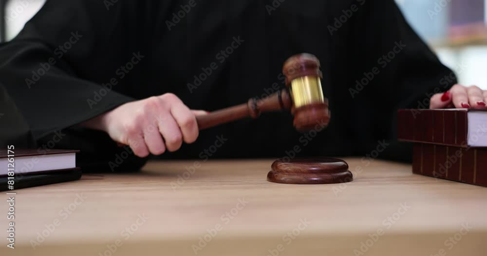 Female judge knocks with wooden gavel on sound block putting hand on law books. Judgement process in court. Equipment of judge slow motion