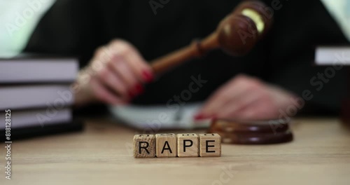 Word Rape made of wooden cubes against judge knocking with gavel. Female judge puts down gavel beginning sexual assault hearing. Justice for criminal photo