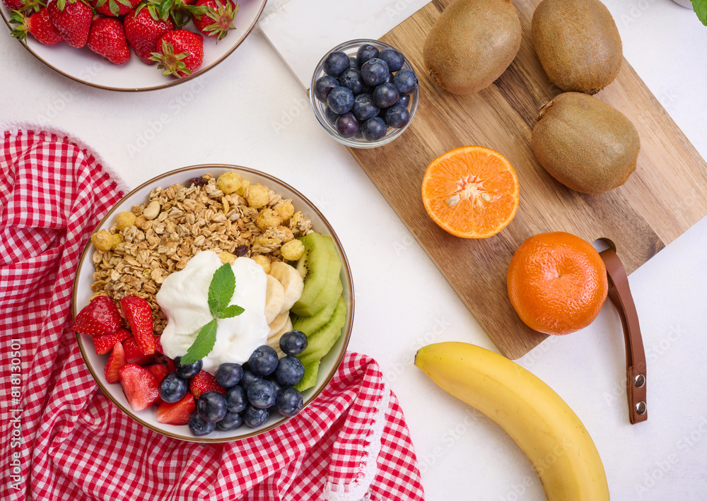 Granola with strawberries, kiwi, banana and blueberries in a round plate on a black table. Healthy and tasty food Granola with strawberries, kiwi, banana and blueberries in a round plate on a black table. Healthy and tasty food