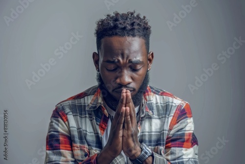 Young african american man praying with hands together, casual clothes, hope expression on face