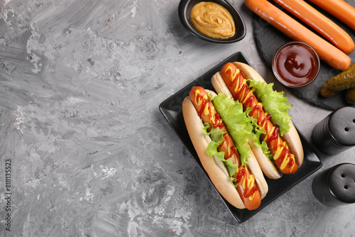 Принти на полотні Tasty hot dogs and ingredients on grey textured table, flat lay
