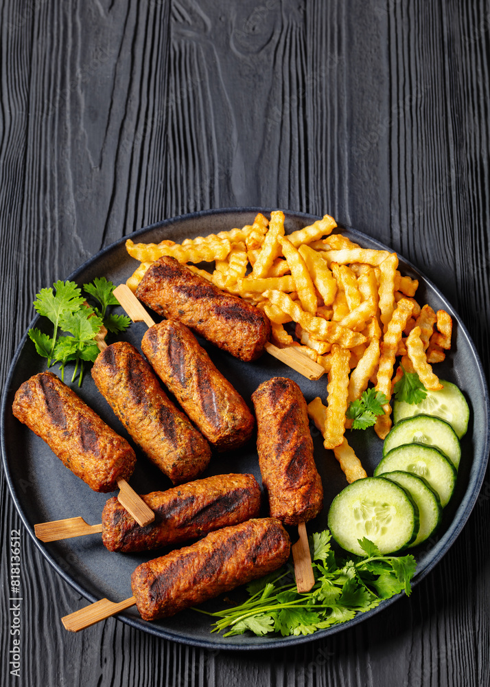 minced beef skewers with potato fries on plate minced beef skewers with potato fries on plate