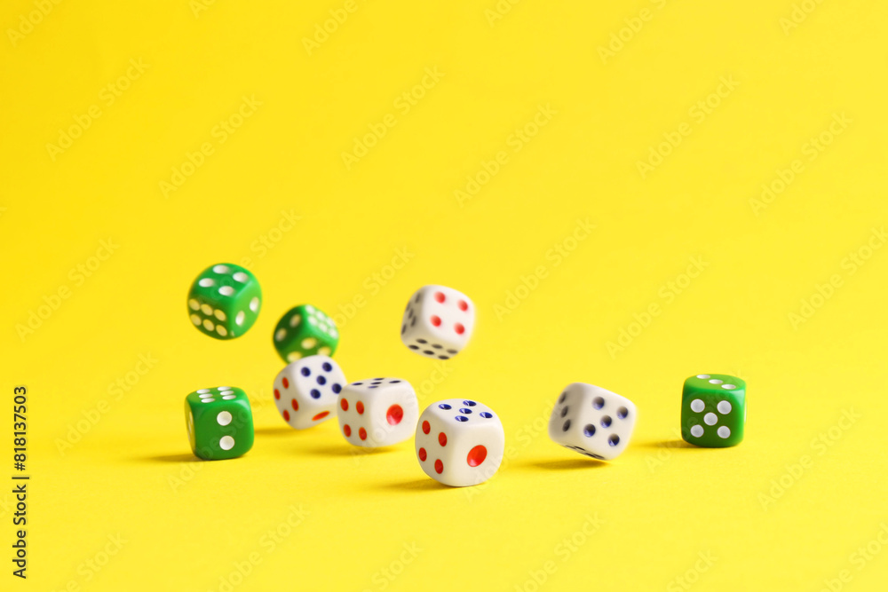 Many color game dices falling on yellow background Many color game dices falling on yellow background