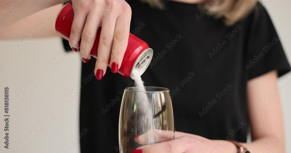 Woman pours sugar into glass from beverage red tin can. High sugar content in sweet carbonated drinks. Harmful effect of sugar on human health