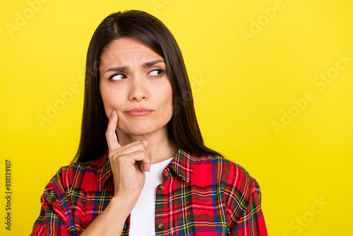 Photo of doubtful attractive lady dressed checkered shirt finger cheek looking empty space isolated yellow color background