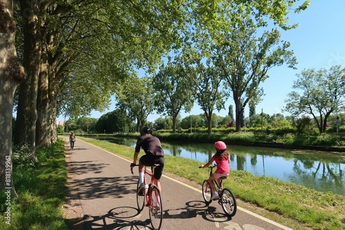 Deux cyclistes (un homme et une fillette) pratiquant le cyclotourisme sur une piste cyclable au bord du canal de Bourgogne, à Dijon, en Côte d’Or (France)