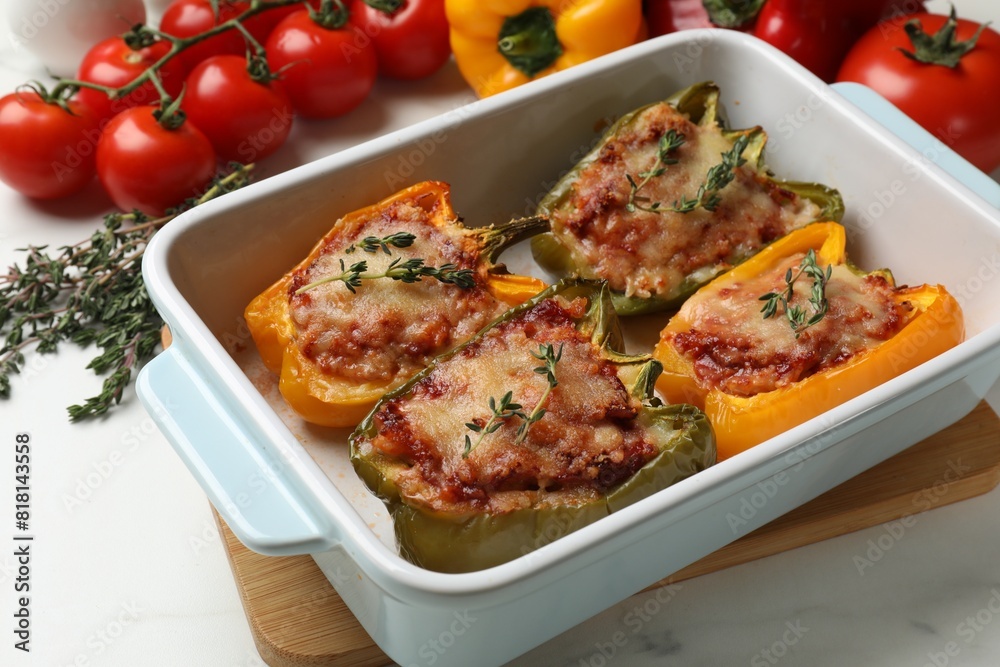 Tasty stuffed peppers in dish and ingredients on white table Tasty stuffed peppers in dish and ingredients on white table