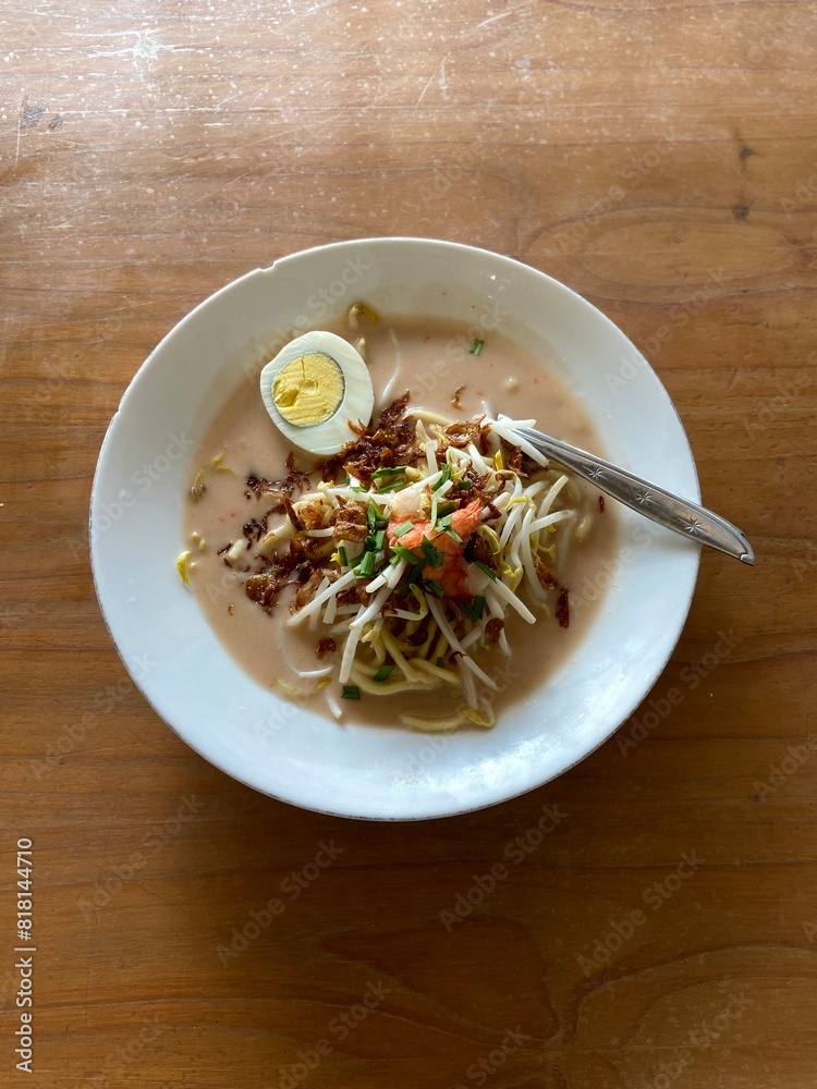 Celor noodles typical of South Sumatra, Indonesia, on a white plate on a wooden table with natural lighting
