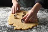 Shortcrust pastry. Woman making cookies with cutters at grey table, closeup