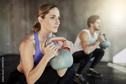Power, squat and couple in gym with kettlebell, fitness training and workout challenge together at sports club. Man, woman or personal trainer with muscle development, healthy body and exercise.
