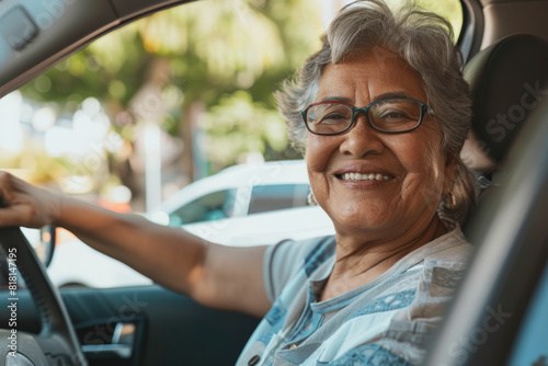 Cheerful Latino senior lady driving her car independently, delighting in the ride. Emphasizing safe driving practices for older adults, ensuring road safety.