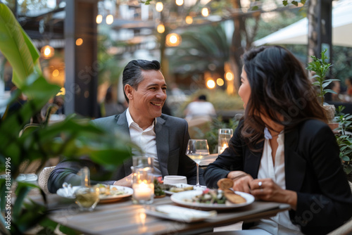 Two Latino managers having a business lunch  discussing a new business project. The couple is seated outdoors on a terrace restaurant  enjoying a dinner date.