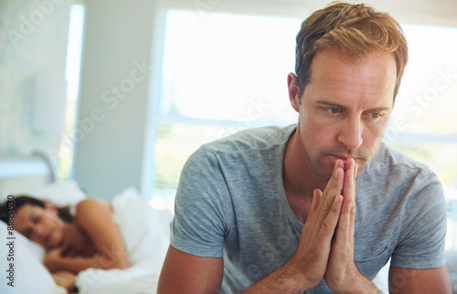 Фотография Thinking, married and man in bedroom at house with stress, anxiety and problem of secret from cheating on sleeping woman