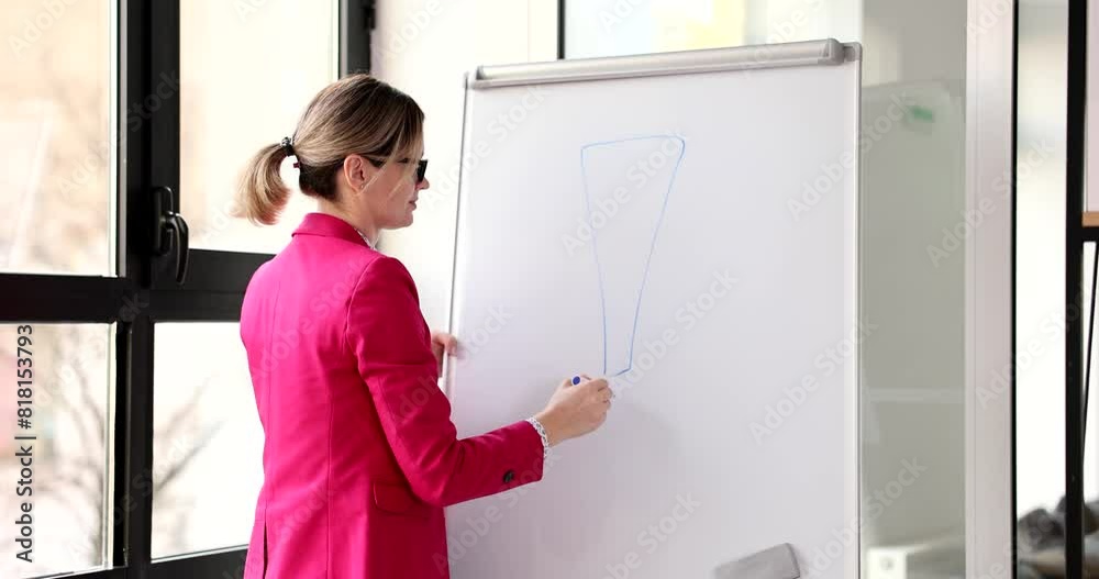 Female employee wearing spectacles draws exclamation mark on white board. Office worker in suit warns colleagues at conference slow motion Female employee wearing spectacles draws exclamation mark on white board. Office worker in suit warns colleagues at conference slow motion
