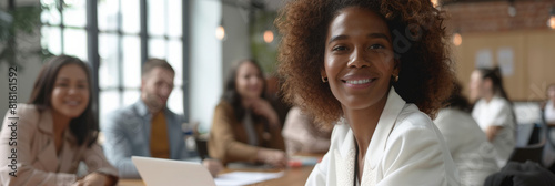 A team of diverse employees convenes in an office for a discussion, meeting, and collaboration on project development. Seated at a table, they engage in constructive dialogue and exchange ideas,