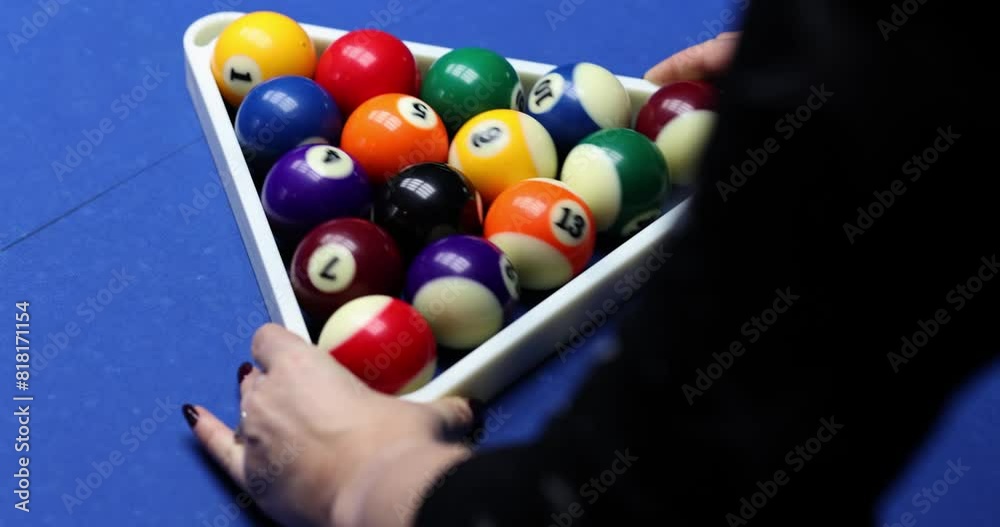 Woman puts balls in triangle rack on billiard table slow motion. Player prepares equipment for game in sports club. Colorful playing spheres